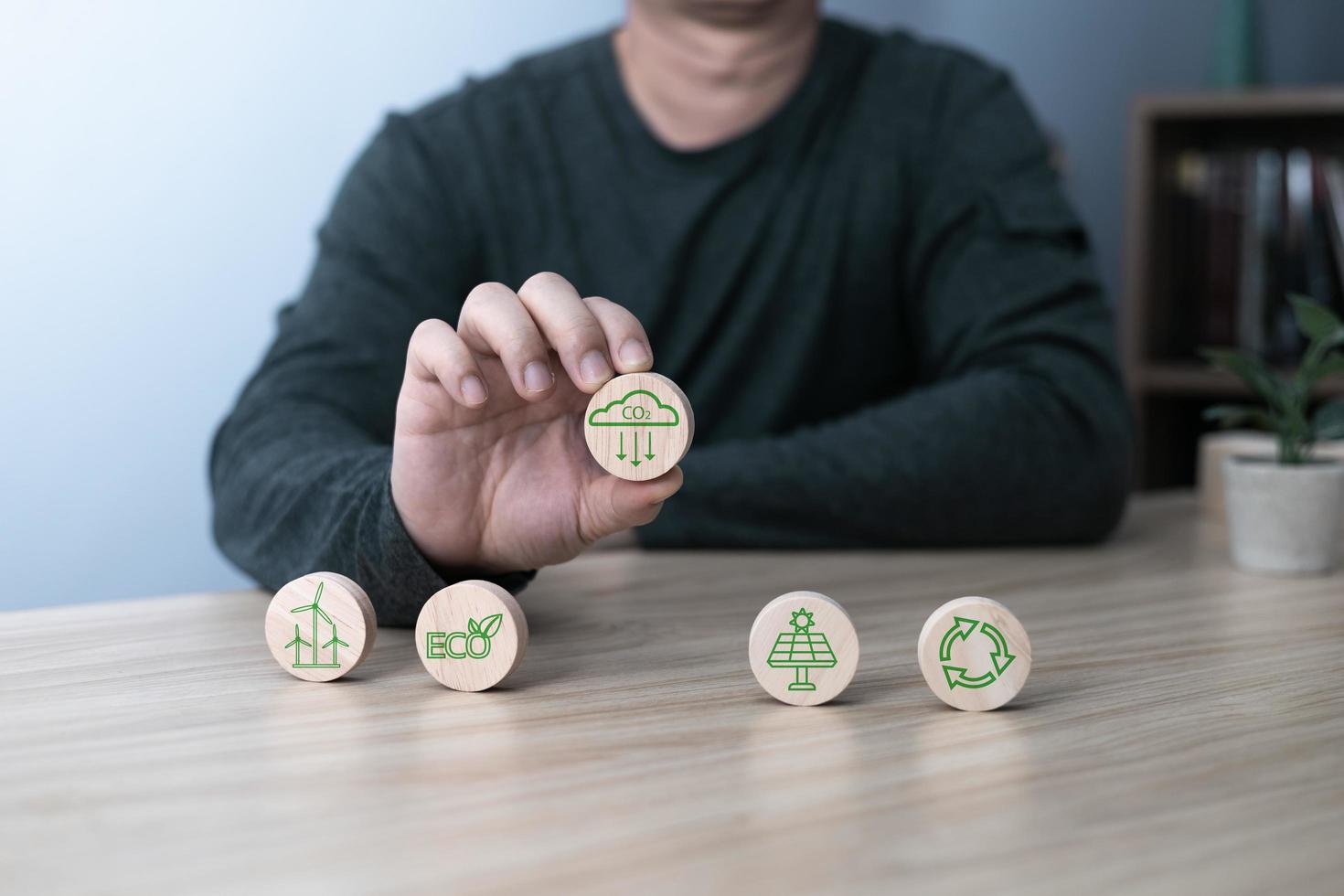 Hand of a businessman chooses reduce co2 icon on wood block circle.idea for environmentally conscious business, climate change, eco-friendly investment,ESG for Environment Social and Governance photo