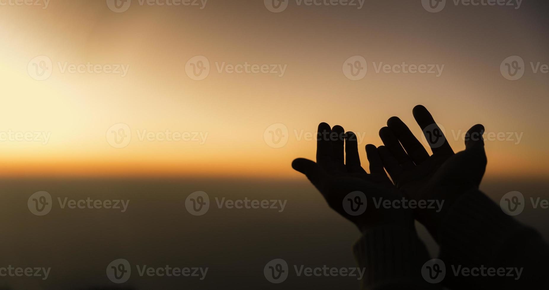 Silhouette of woman hands praying for worship God at sky background. Christians pray to jesus christ for calmness. In morning people got to a quiet place and prayed. Banner with copy space. photo