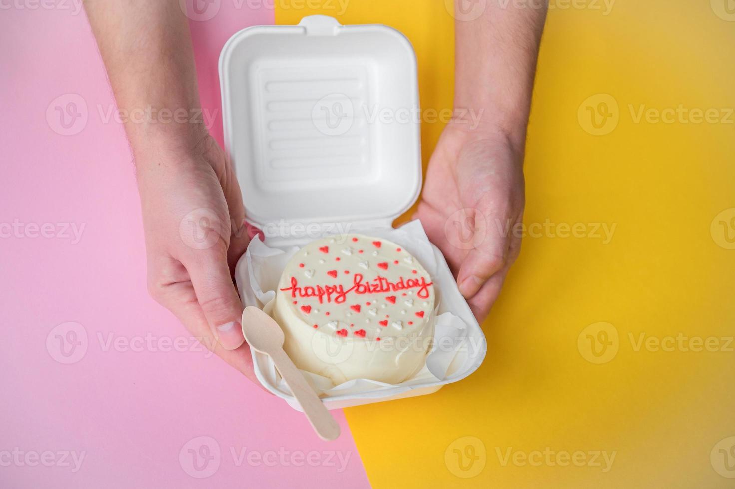 A man's hands hold a festive bento cake with birthday and hearts photo