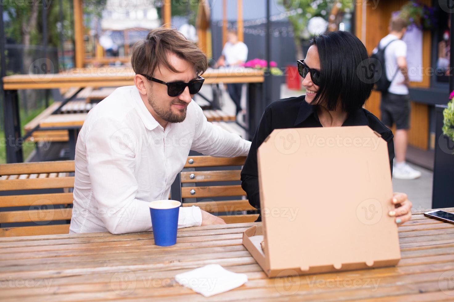 An emotional woman and a man look into an open pizza box photo