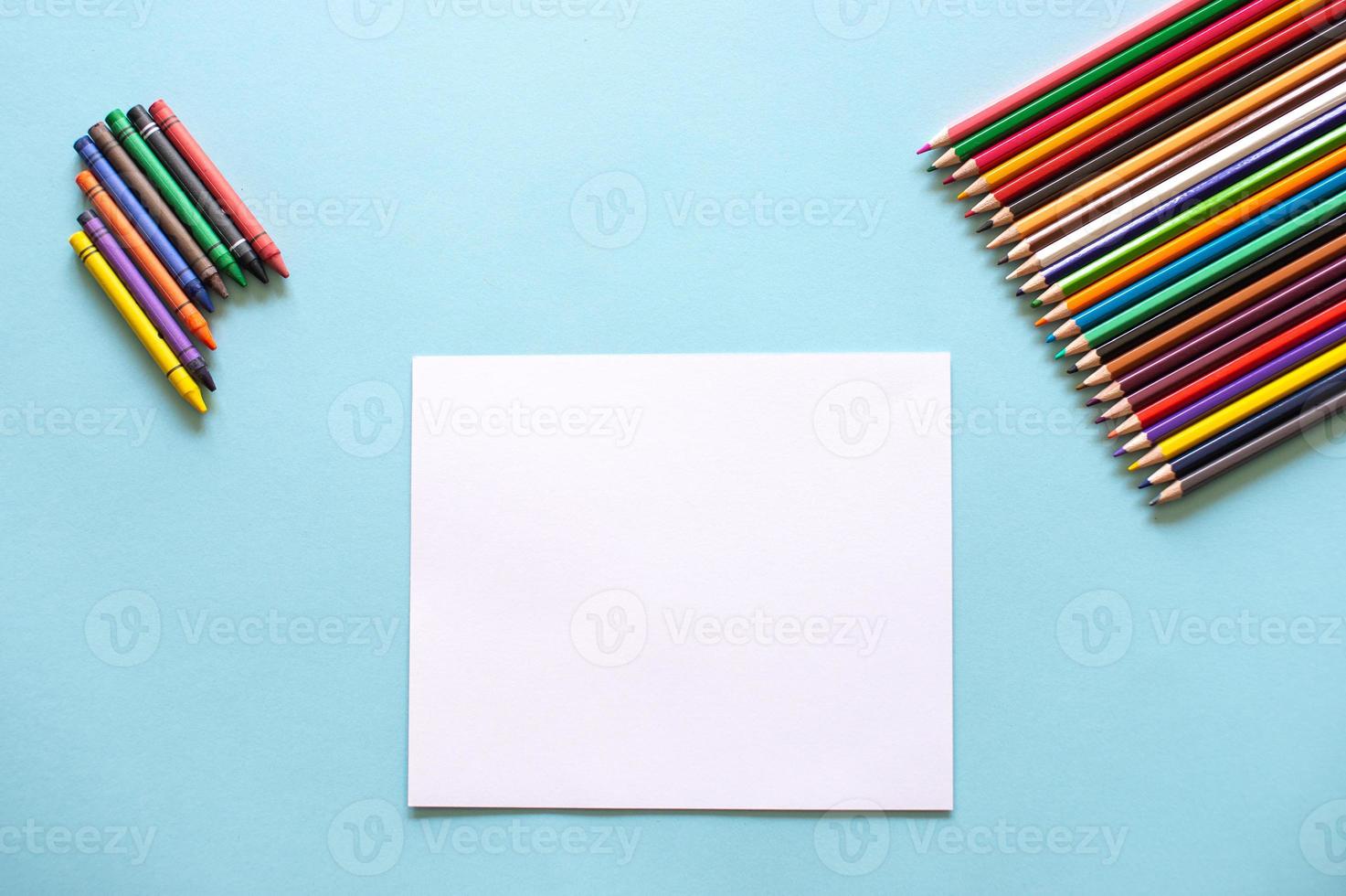 A set of bright stationery on a blue background. colored pencils and white paper photo