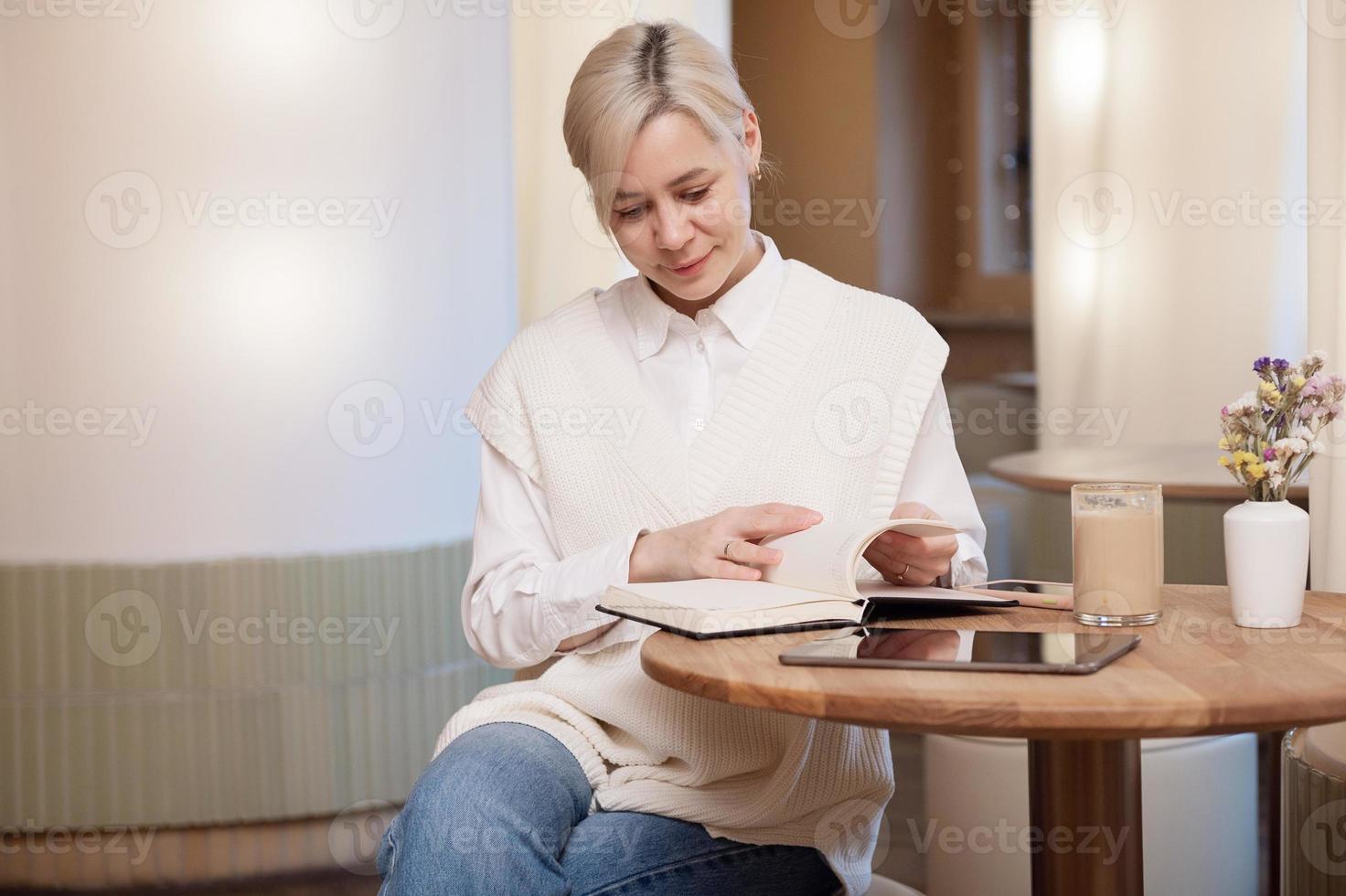 linda niña en un camisa voltear mediante un diario en un café foto