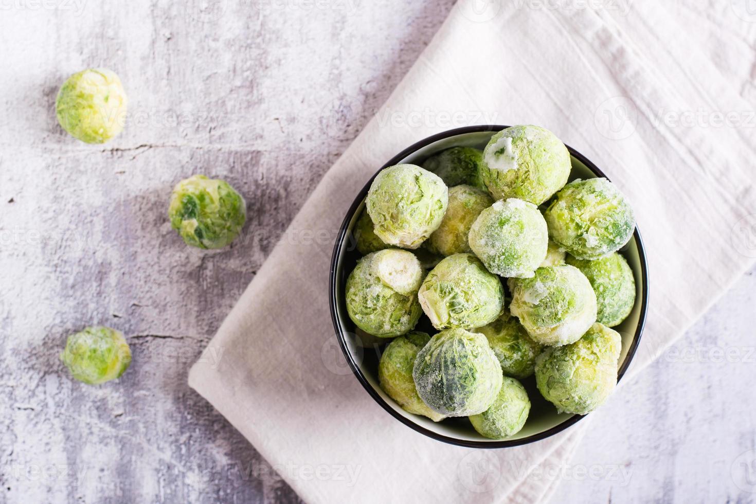 Frozen Brussels sprouts in a bowl on a gray background. Vegetarian food. Top view. Closeup photo