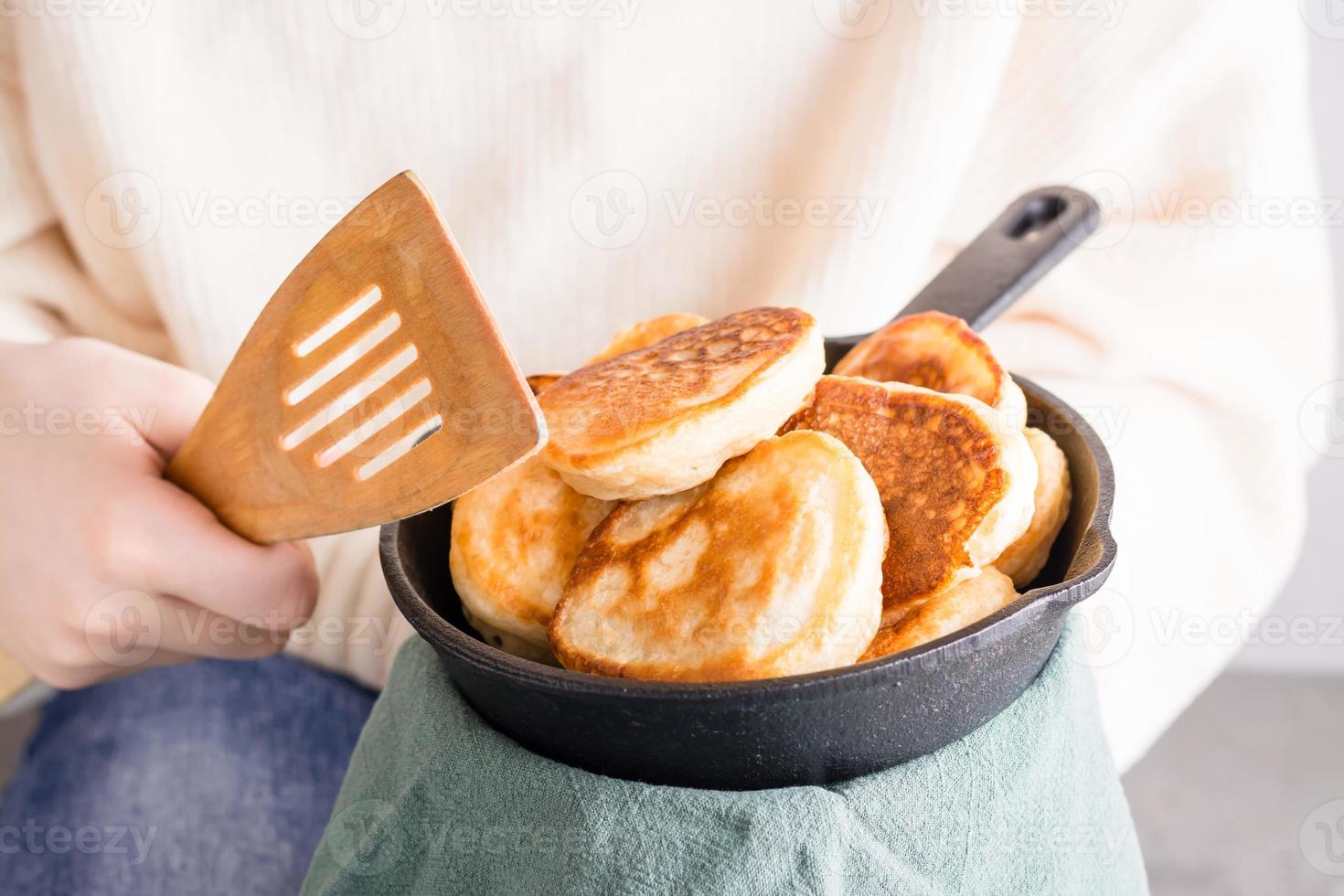 The child holds in his hands a frying pan with pancakes and a spatula for frying. Lifestyle with food photo