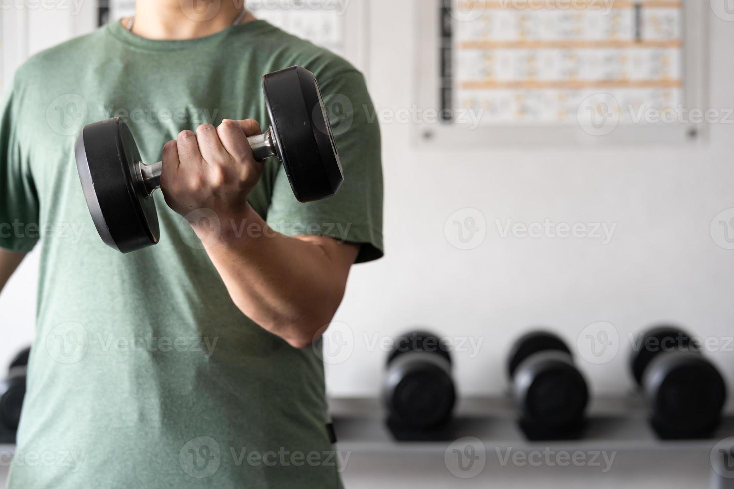 man workout in the indoor gym, man lifting up a Hammer Curl weight exercise. bodybuilding dumbbells in gym. training in fitness gym. photo