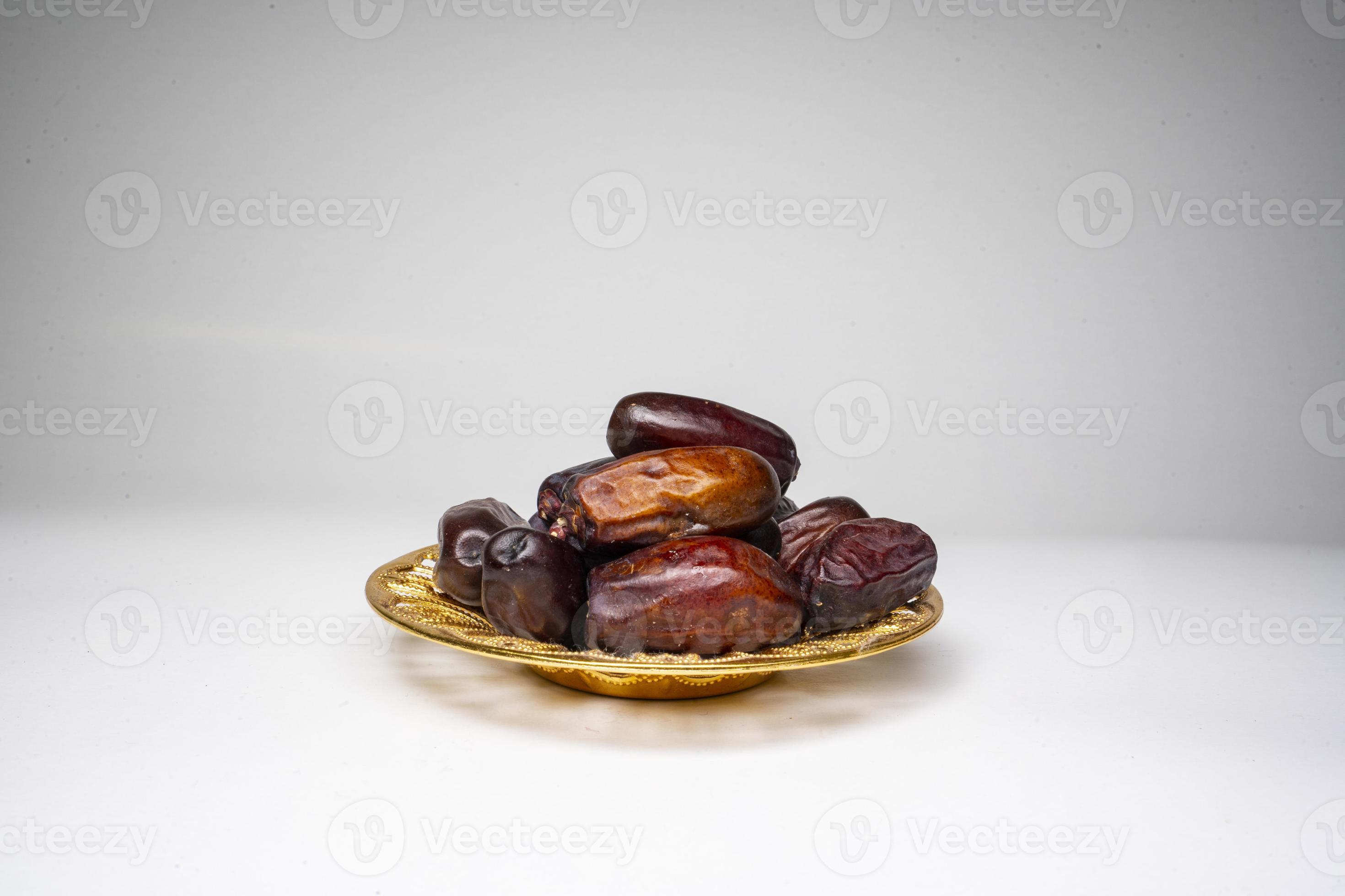 photo a small bowl of dates next to a handful on white background high photo a small bowl of dates next to a handful on white background high