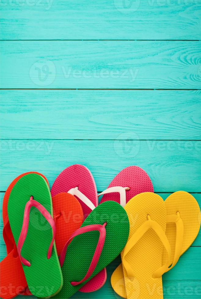 Summer Colorful flip flops on blue wooden background with copy space. Top view and selective focus. Mock up. photo
