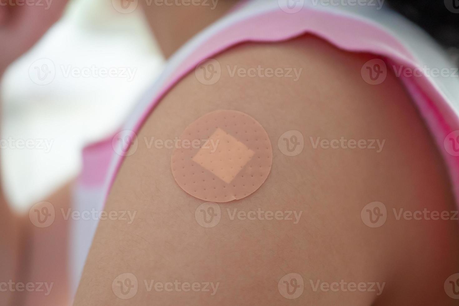 Vaccinated little asian girl with adhesive plaster after vaccine injection photo