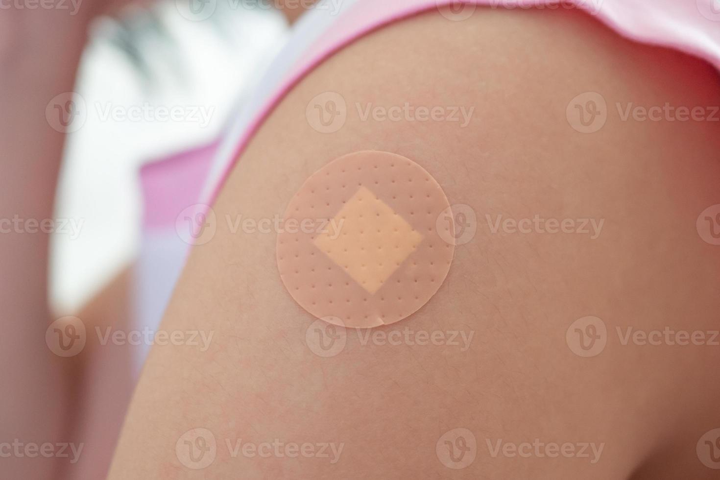 Vaccinated little asian girl with adhesive plaster after vaccine injection photo