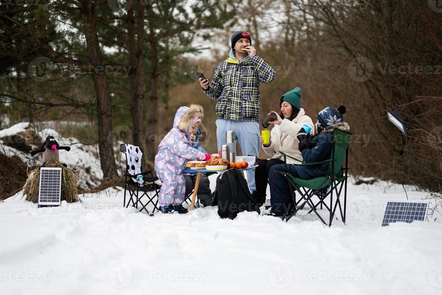 Family with three children in winter forest spending time together on a picnic. photo