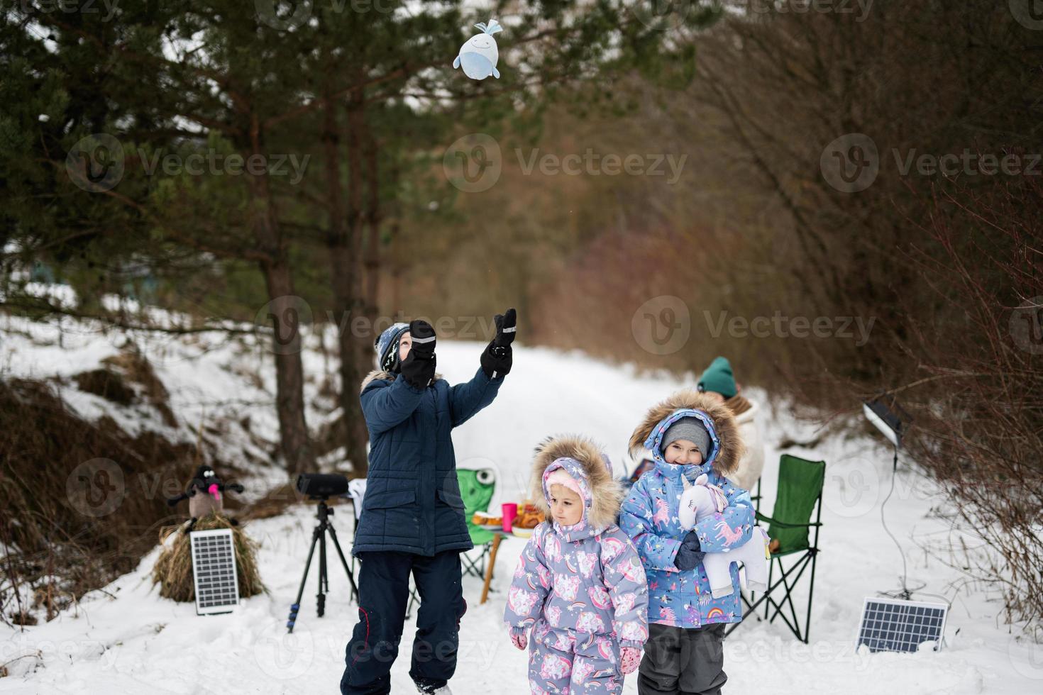 Children in winter forest on a picnic with stuffed toys at hands. photo