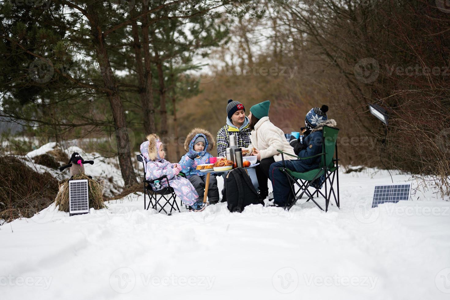 Family with three children in winter forest spending time together on a picnic. photo