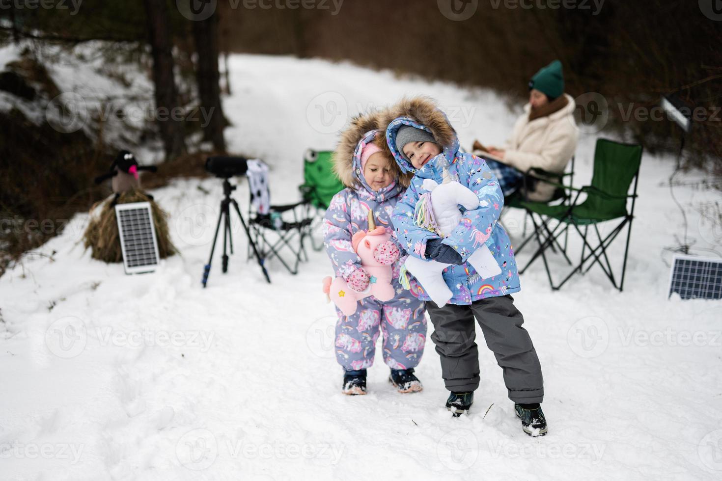 Two sisters in winter forest with stuffed unicorn toys. photo