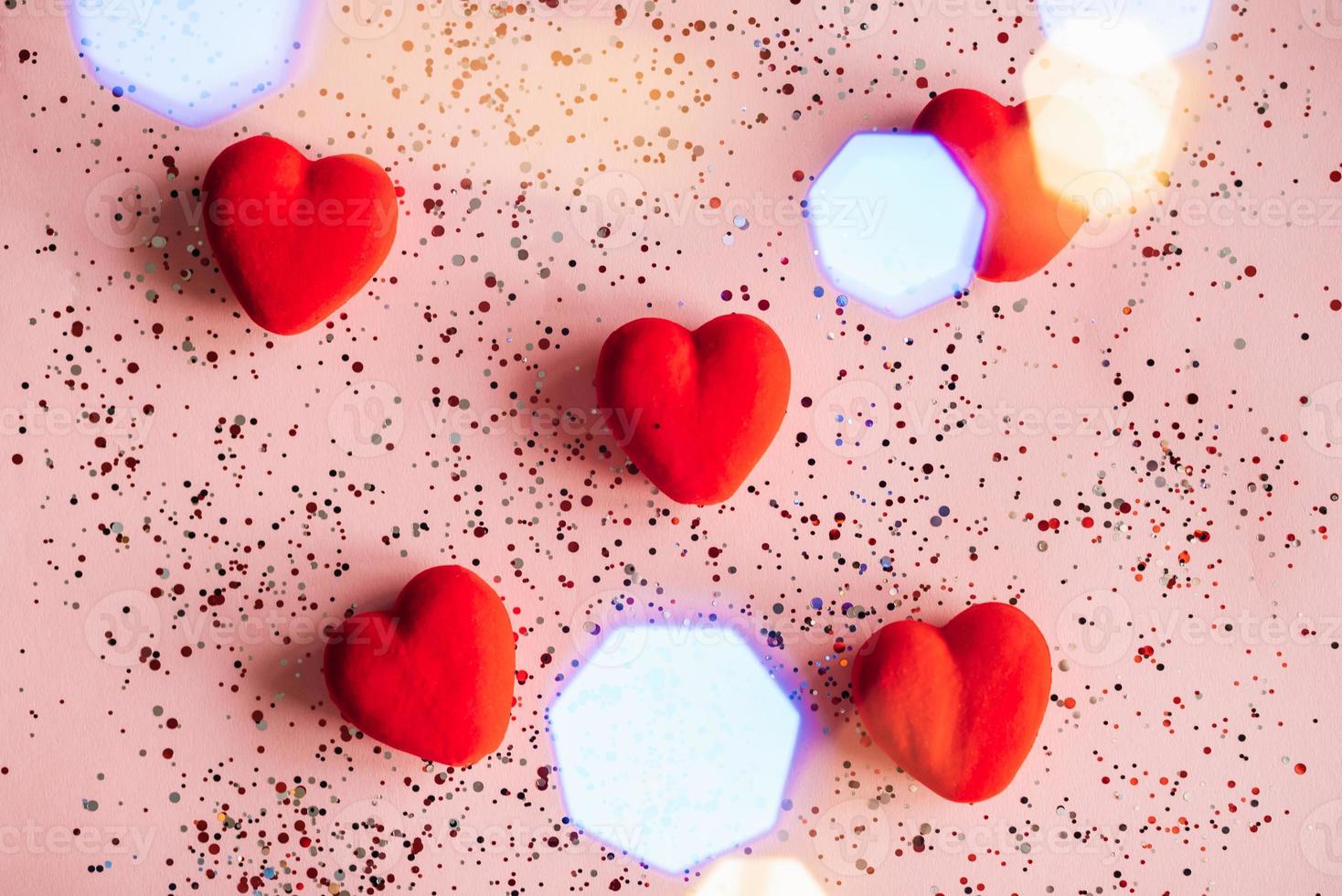 Red hearts on pink background with confetti. Valentine's Day template photo