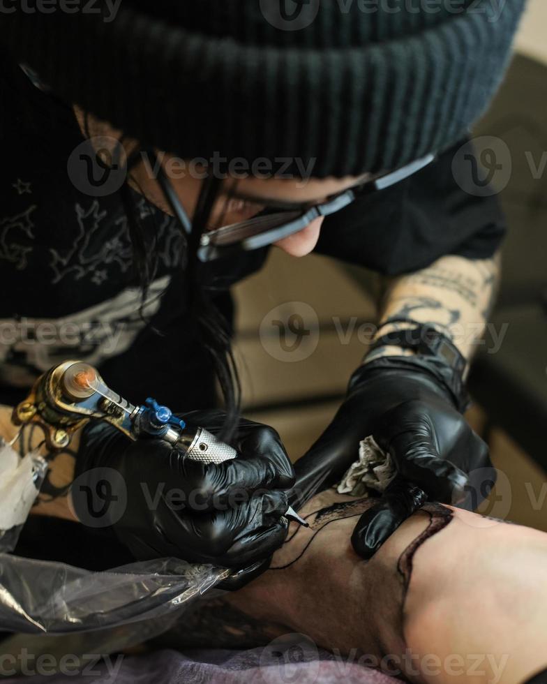 Professional tattoo artist stuffs a tattoo on the man's hand. Tattoo artist at work. Tattoo creation process. Art and creativity photo