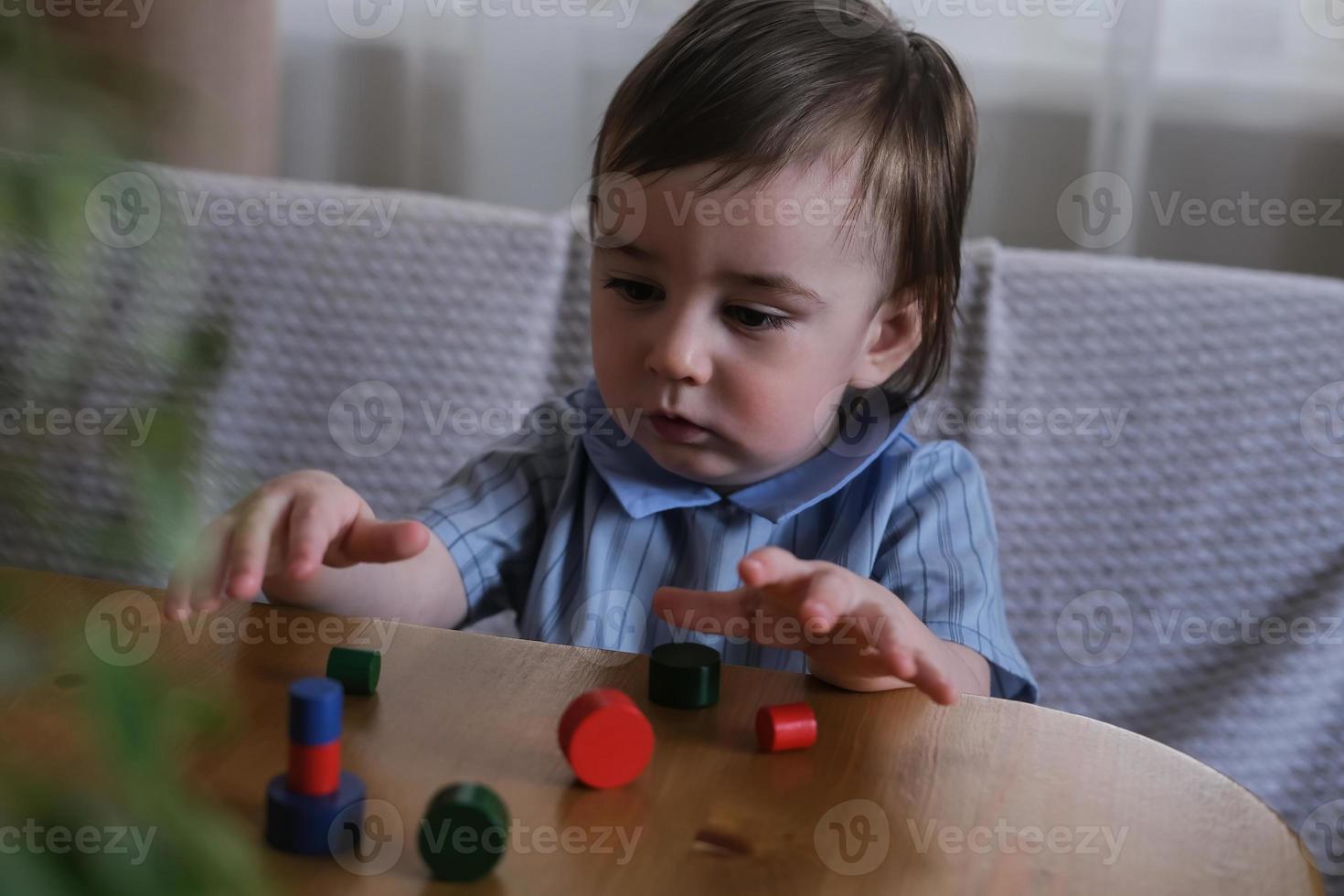 A one-year-old child plays with multi-colored wooden figurines. Development of fine motor skills and logical thinking of kids photo