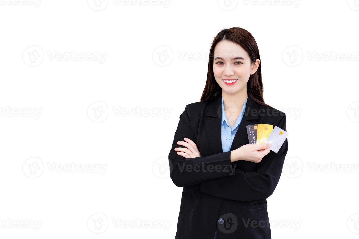 profesional asiático negocio mujer en formal negro traje en pie con confianza sonriente y mirando a el cámara sostiene y muestra crédito tarjeta en su mano aislado en blanco antecedentes. financiero concepto. foto