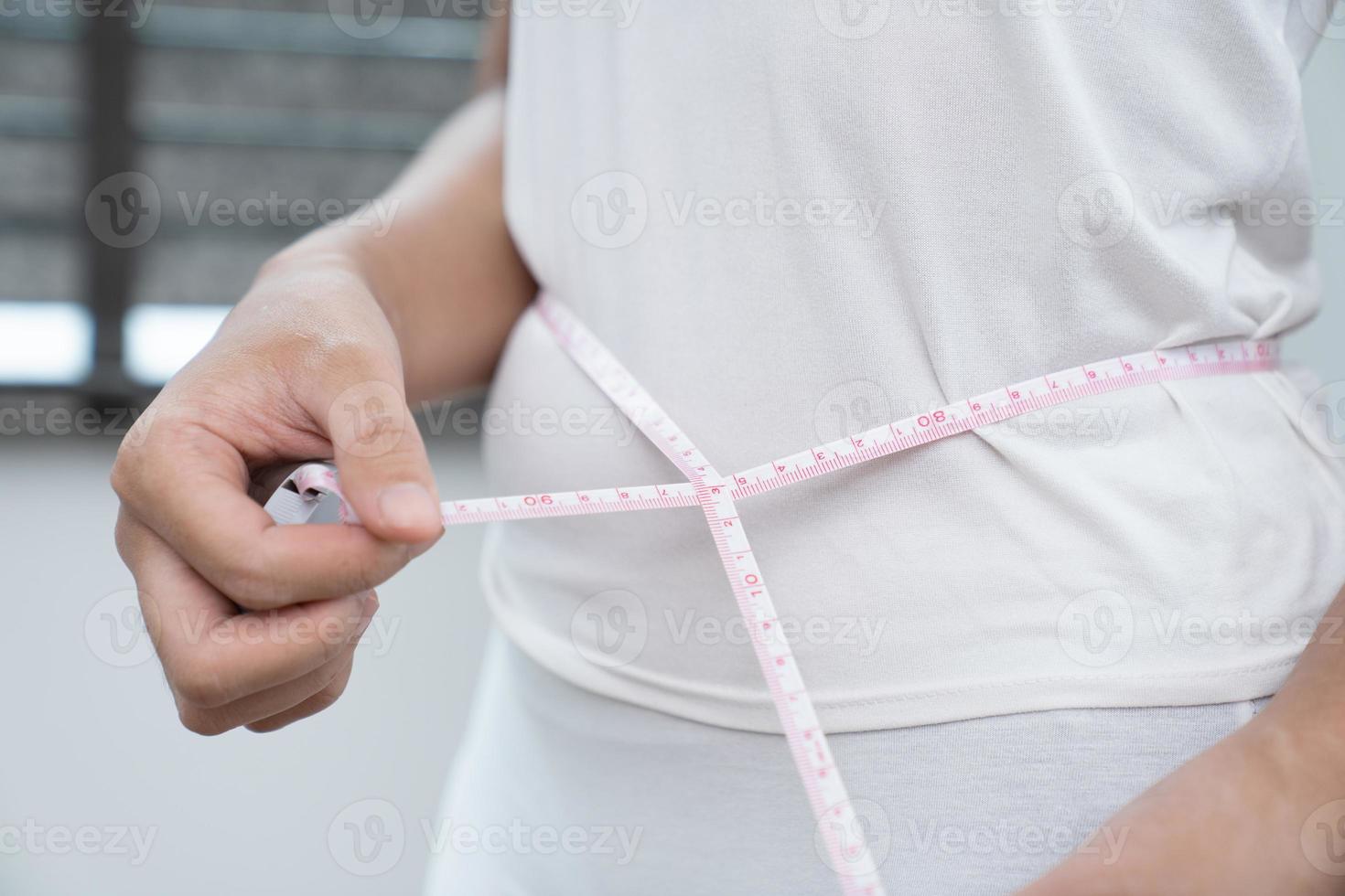 Concept of weight loss. Girl holds jeans in her hand and shows a thin waist and measures her waist with a centimeter. Diet concept photo