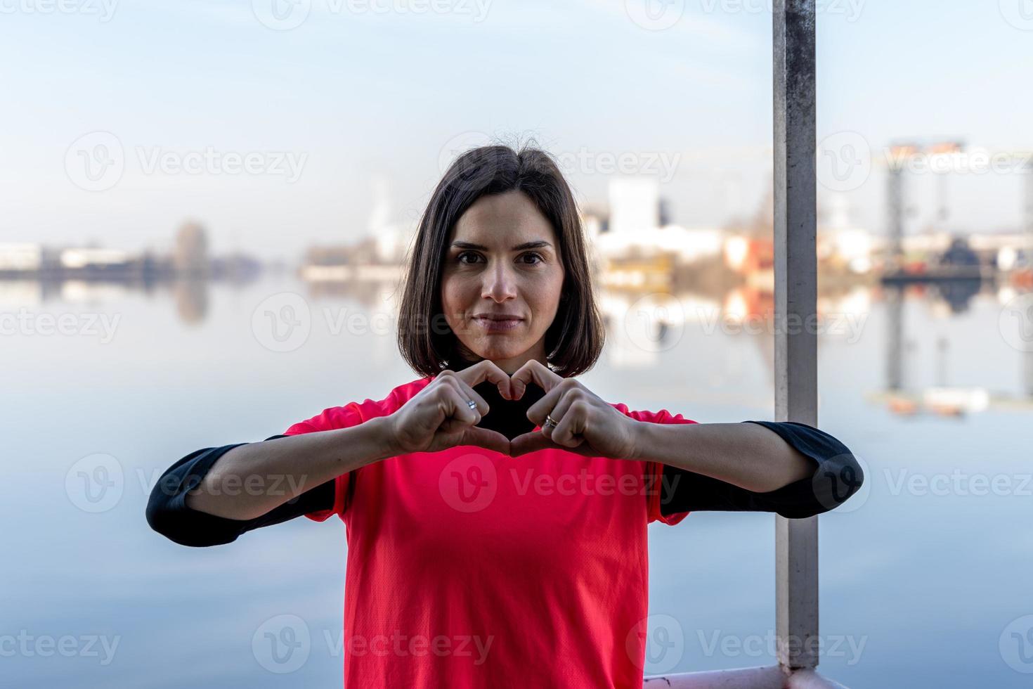 cute young woman showing heart sign with hands on a boat photo