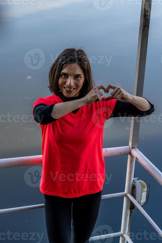 linda joven mujer demostración corazón firmar con manos en un barco foto