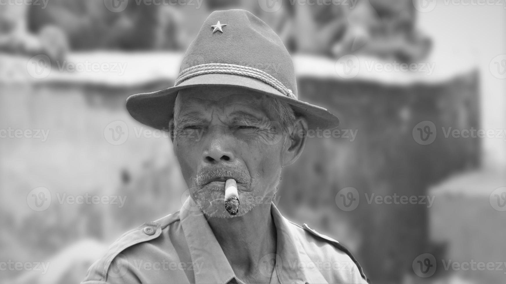 old man smoking a cigarette, emitting smoke, with blur background photo