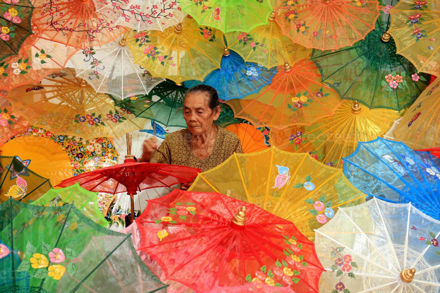 old grandmother's worker painting a traditional umbrella, in klaten, indonesia photo