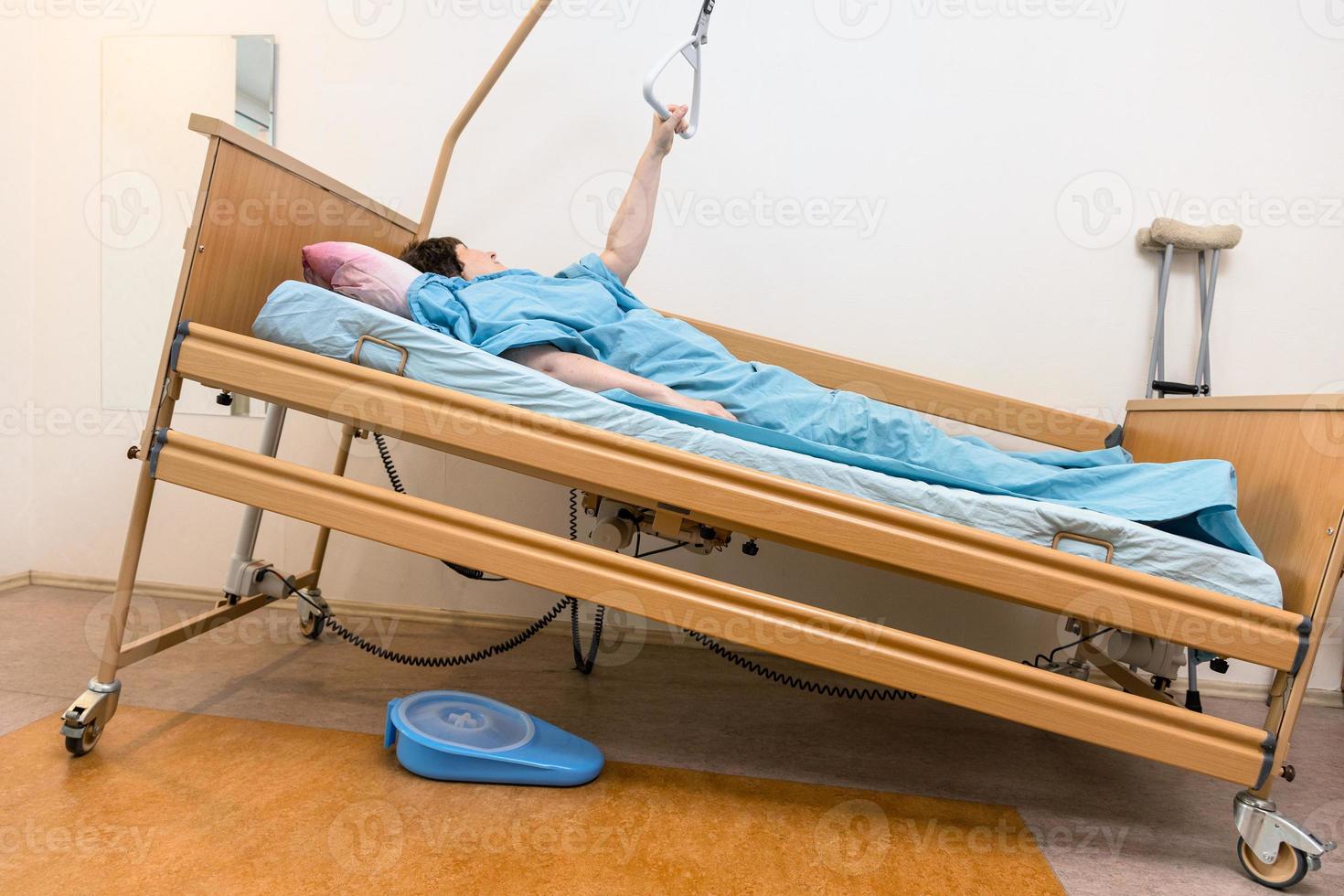 sloped hospital bed with patient holding handle photo