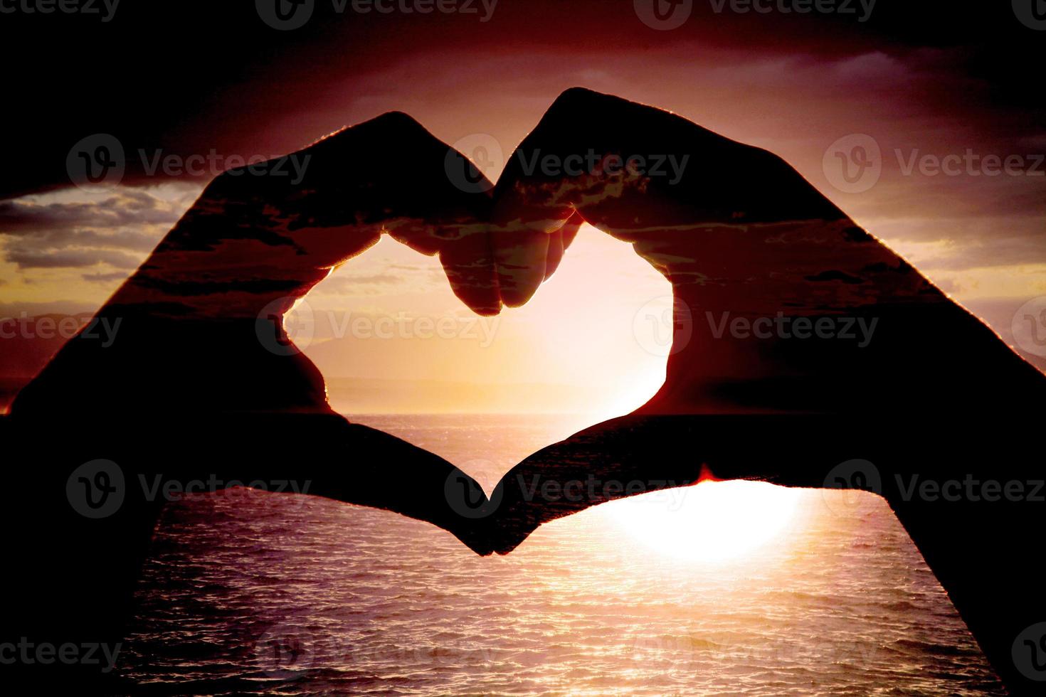 corazón en forma de mano contra la puesta de sol. concepto del día de san valentín foto
