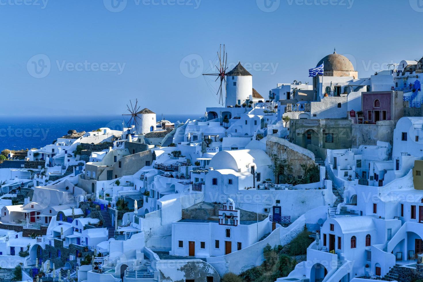Charming view Oia village on Santorini island, Greece. Traditional famous blue dome church over the Caldera in Aegean sea. Traditional blue and white Cyclades architecture. photo