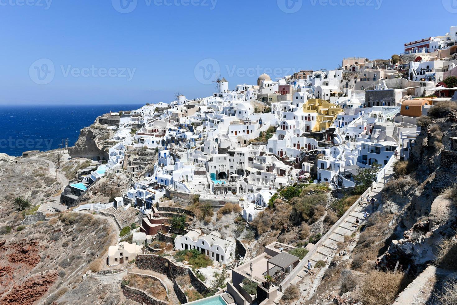 Charming view Oia village on Santorini island, Greece. Traditional famous blue dome church over the Caldera in Aegean sea. Traditional blue and white Cyclades architecture. photo