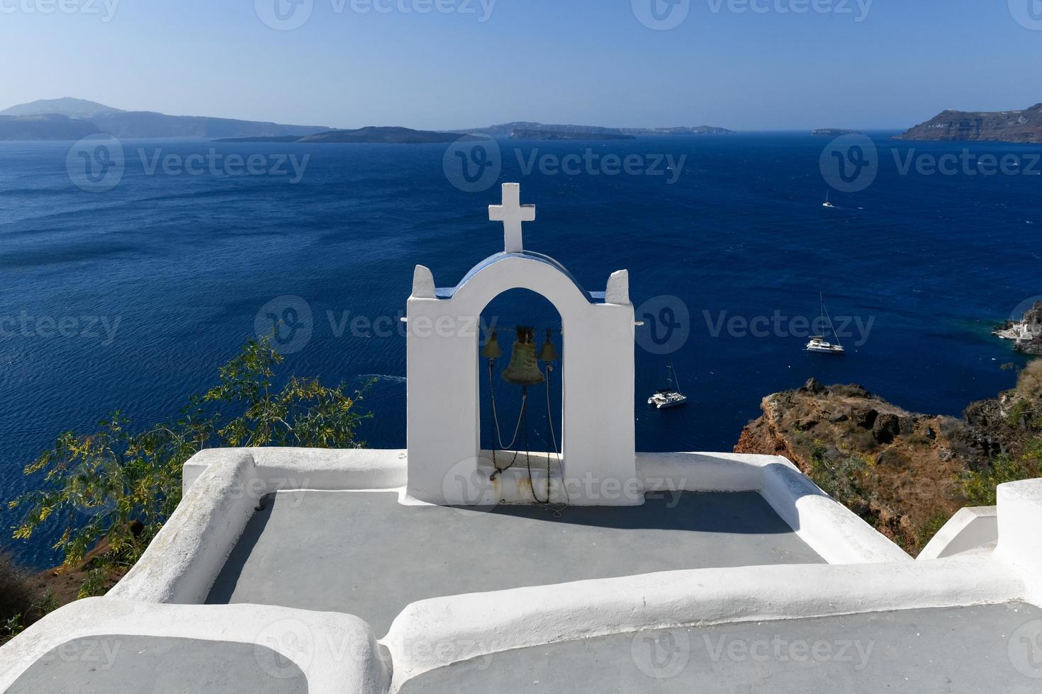 Charming view Oia village on Santorini island, Greece. Traditional famous blue dome church over the Caldera in Aegean sea. Traditional blue and white Cyclades architecture. photo