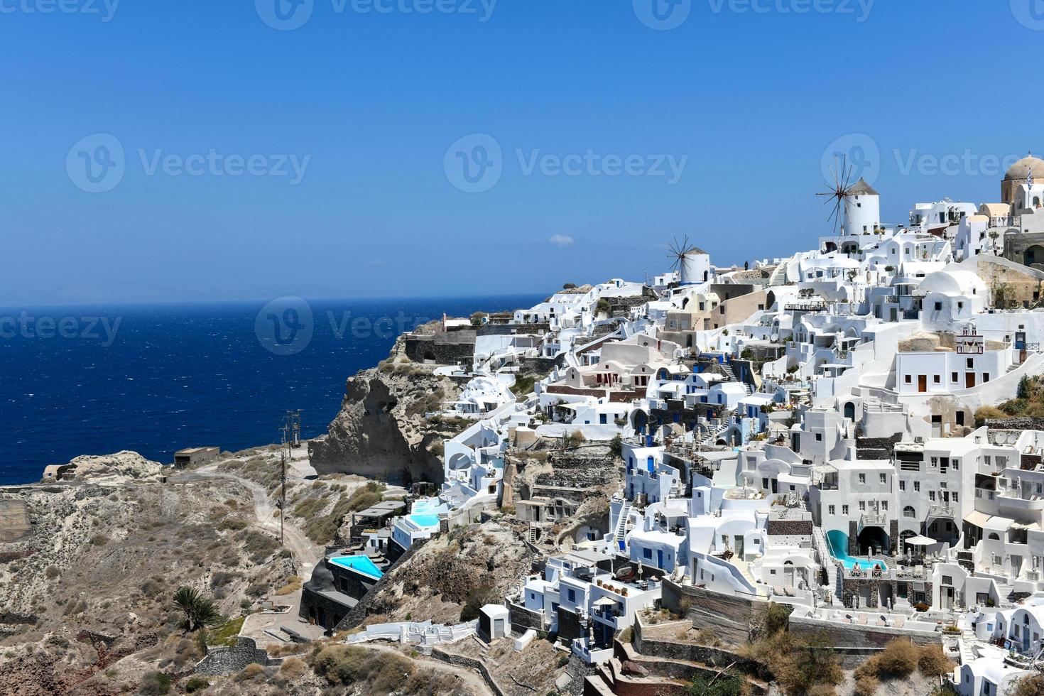 Charming view Oia village on Santorini island, Greece. Traditional famous blue dome church over the Caldera in Aegean sea. Traditional blue and white Cyclades architecture. photo