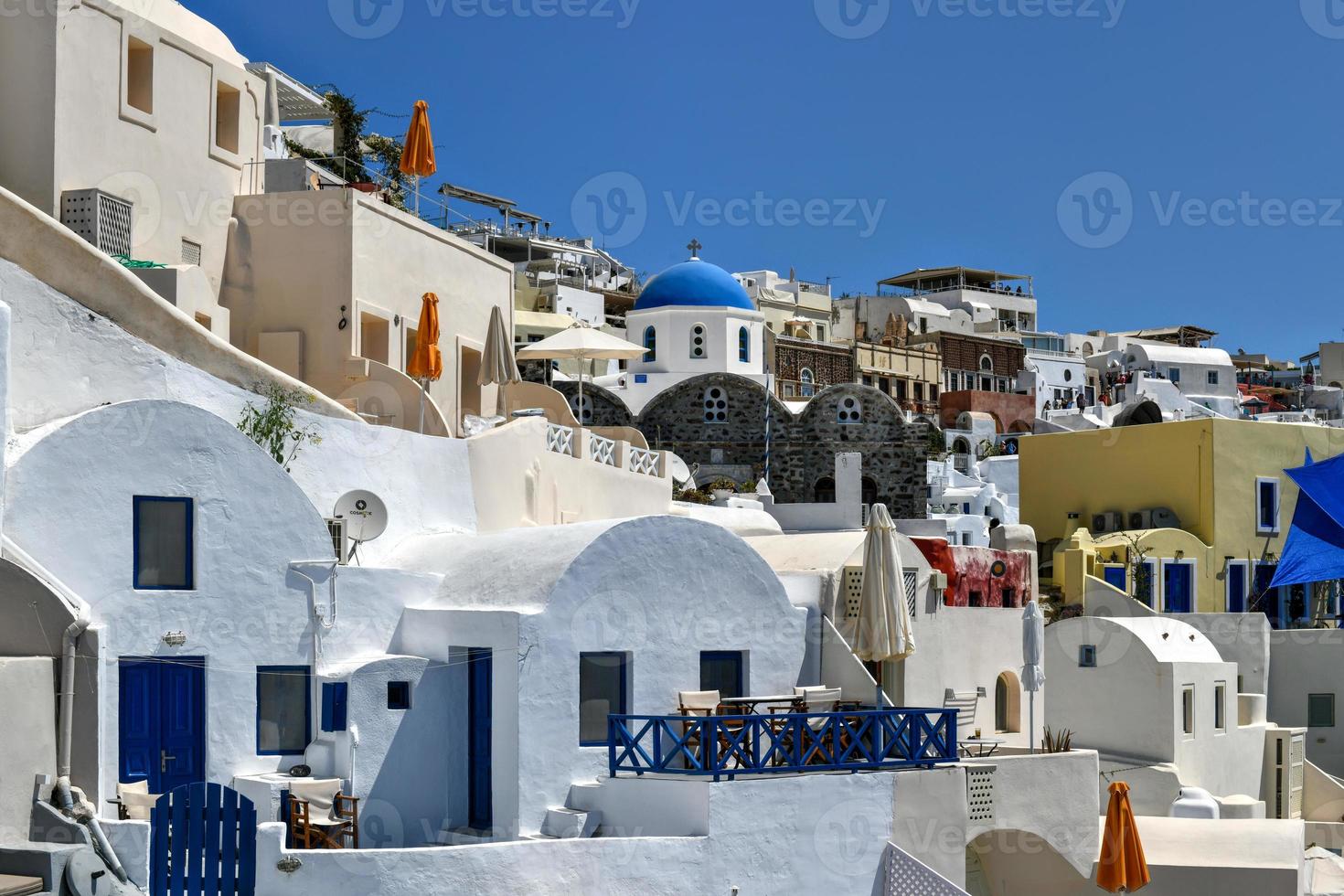 Charming view Oia village on Santorini island, Greece. Traditional famous blue dome church over the Caldera in Aegean sea. Traditional blue and white Cyclades architecture. photo
