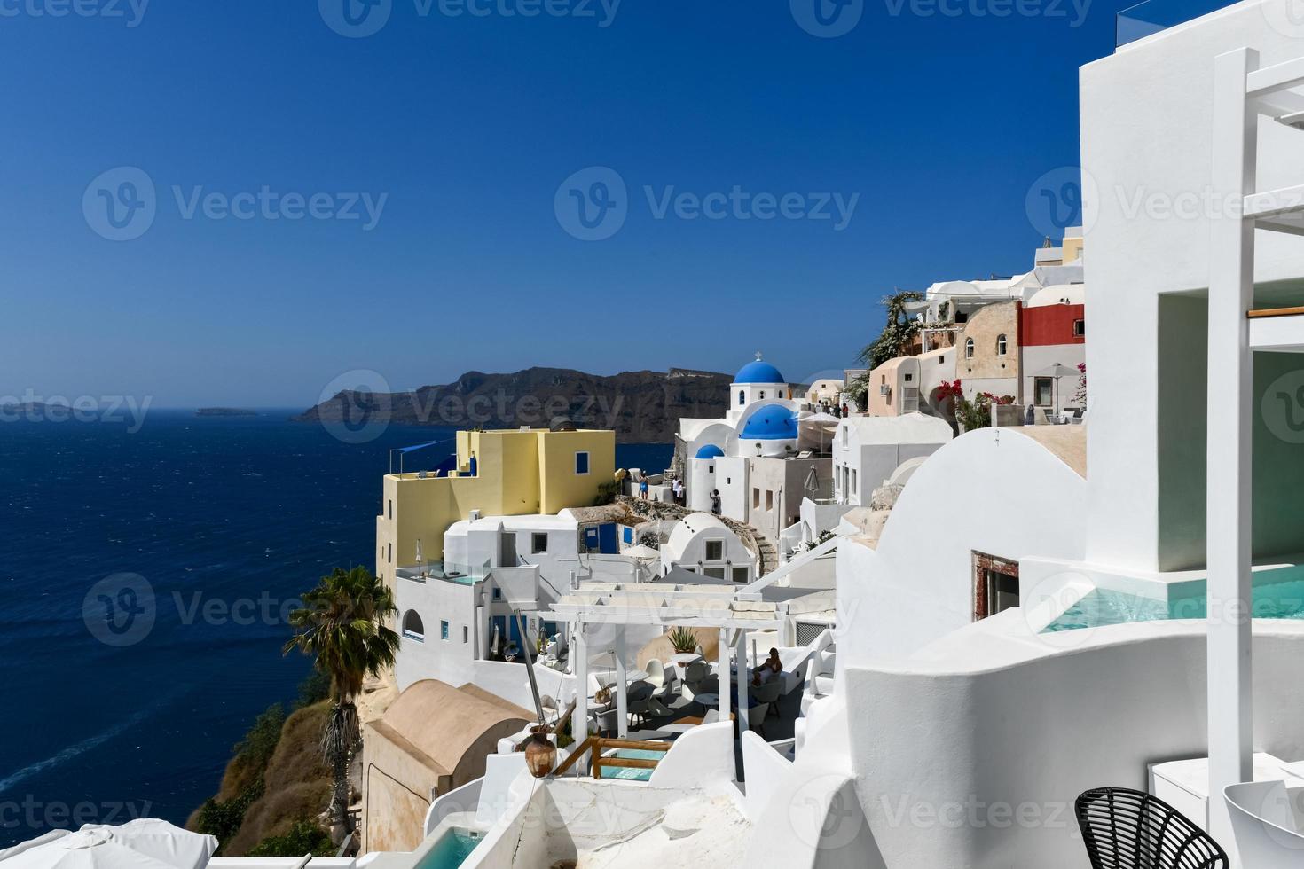 Oia, Greece - Jul 23, 2021, Charming view Oia village on Santorini island, Greece. Traditional famous blue dome church over the Caldera in Aegean sea. Traditional blue and white Cyclades architecture. photo