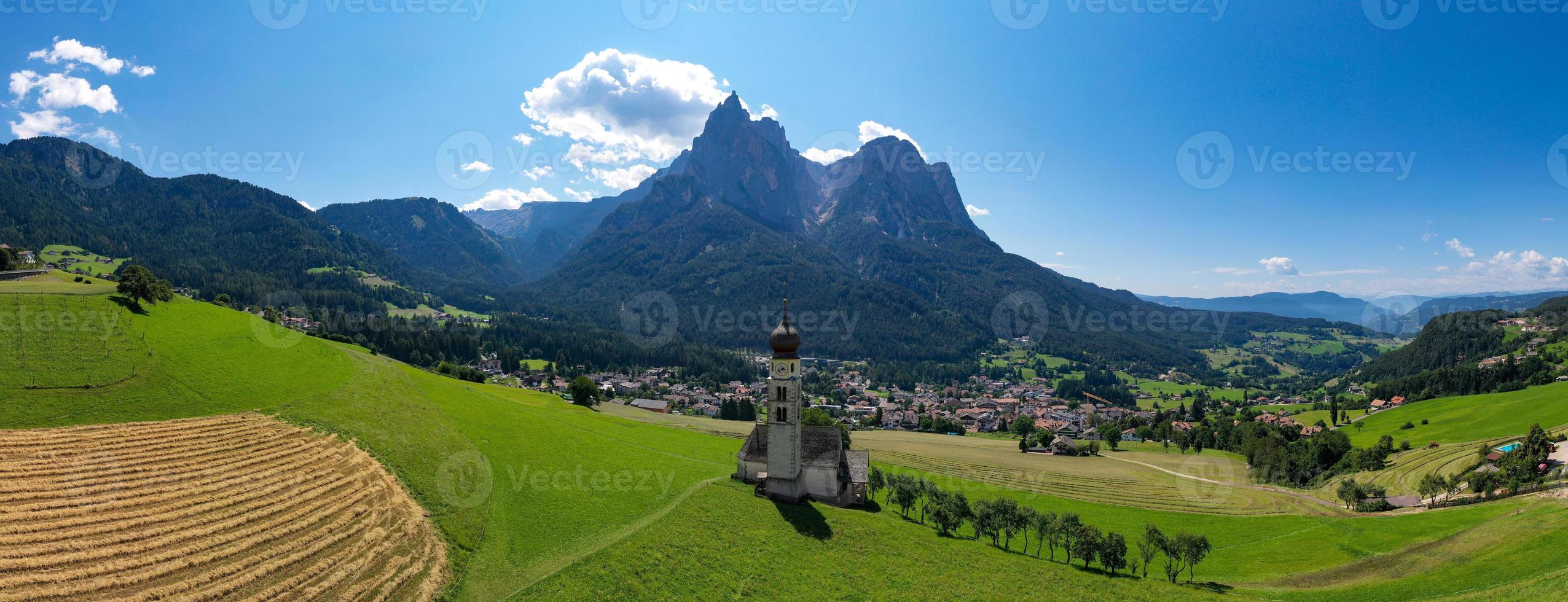 S t. valentin castelruth pueblo Iglesia en el verano en el dolomita Alpes. increíble paisaje con pequeño capilla en soleado prado y mascotas pico a castelruth comuna. dolomitas, sur Tirol, Italia foto