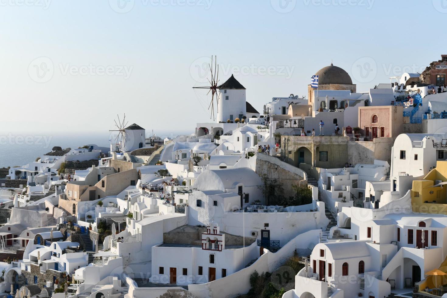 Oia, Greece - Jul 23, 2021, Charming view Oia village on Santorini island, Greece. Traditional famous blue dome church over the Caldera in Aegean sea. Traditional blue and white Cyclades architecture. photo