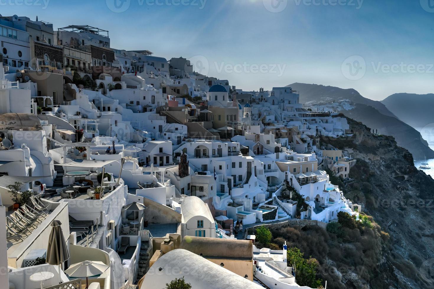 Charming view Oia village on Santorini island, Greece. Traditional famous blue dome church over the Caldera in Aegean sea. Traditional blue and white Cyclades architecture. photo