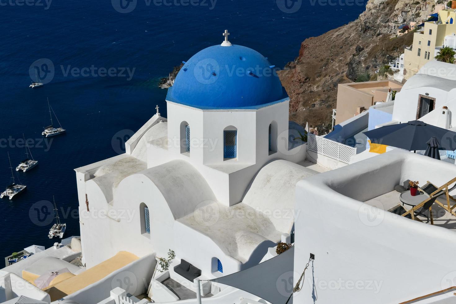 Charming view Oia village on Santorini island, Greece. Traditional famous blue dome church over the Caldera in Aegean sea. Traditional blue and white Cyclades architecture. photo