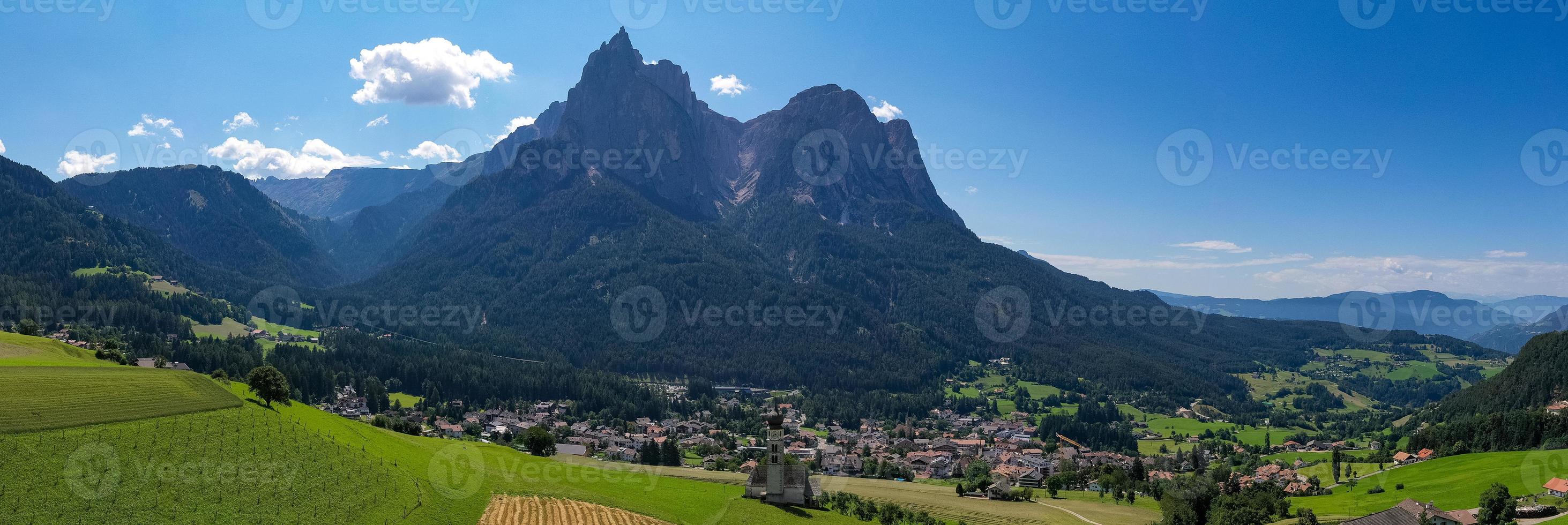 S t. valentin castelruth pueblo Iglesia en el verano en el dolomita Alpes. increíble paisaje con pequeño capilla en soleado prado y mascotas pico a castelruth comuna. dolomitas, sur Tirol, Italia foto