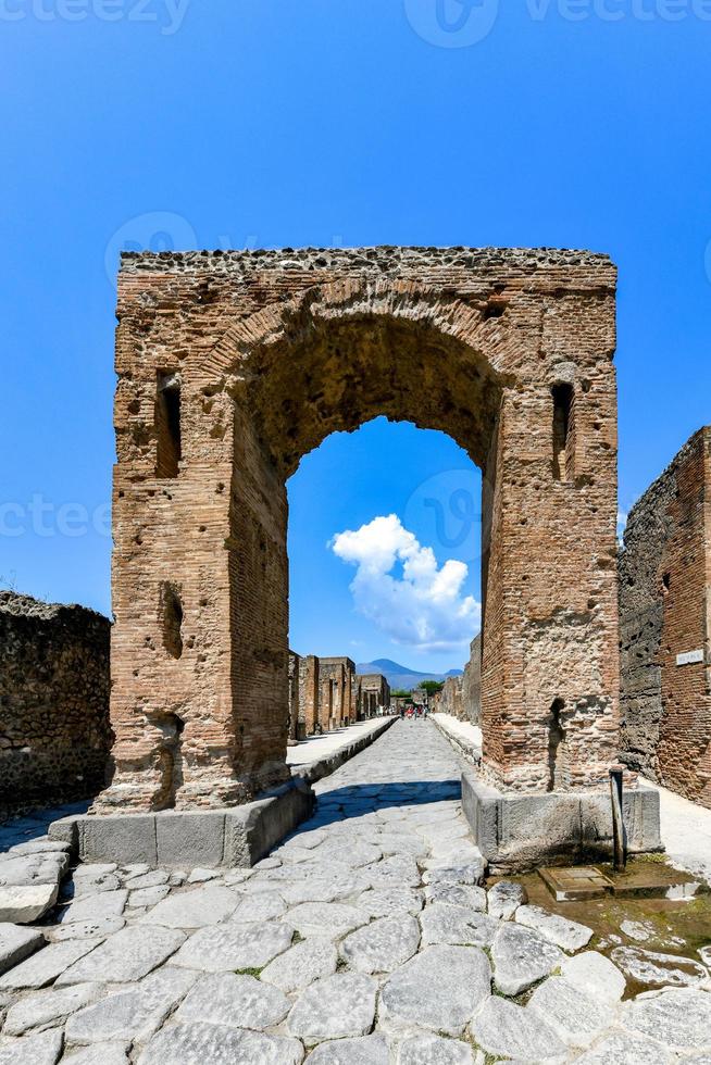 The Caligula Triumphal Arch in Ancient Pompeii, Italy. Looking north through the Arch of Caligula into Via di Mercurio, from crossroads of Via delle Terme, on left, and Via della Fortuna, on right. photo