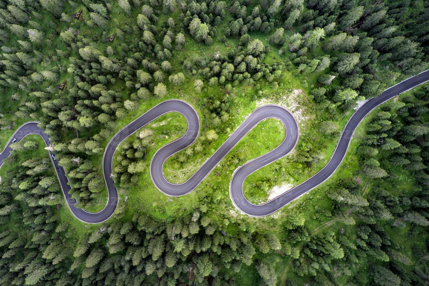 Top aerial view of famous Snake road near Passo Giau in Dolomite Alps. Winding mountains road in lush forest with green spruce in summer time in the Dolomites, Italy photo