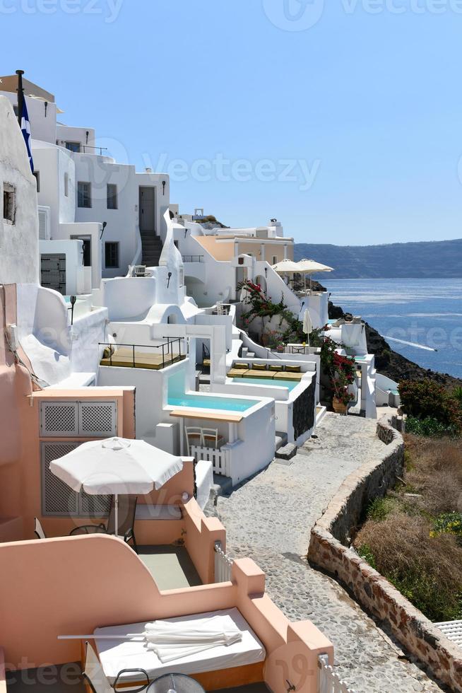 Charming view Oia village on Santorini island, Greece. Traditional famous blue dome church over the Caldera in Aegean sea. Traditional blue and white Cyclades architecture. photo