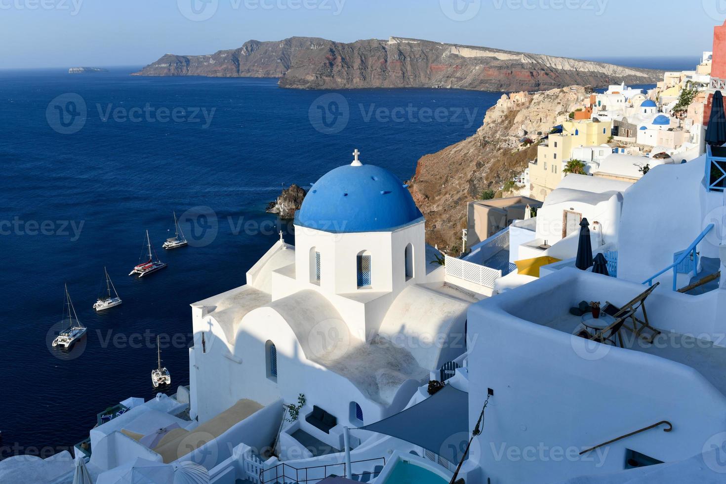 Charming view Oia village on Santorini island, Greece. Traditional famous blue dome church over the Caldera in Aegean sea. Traditional blue and white Cyclades architecture. photo