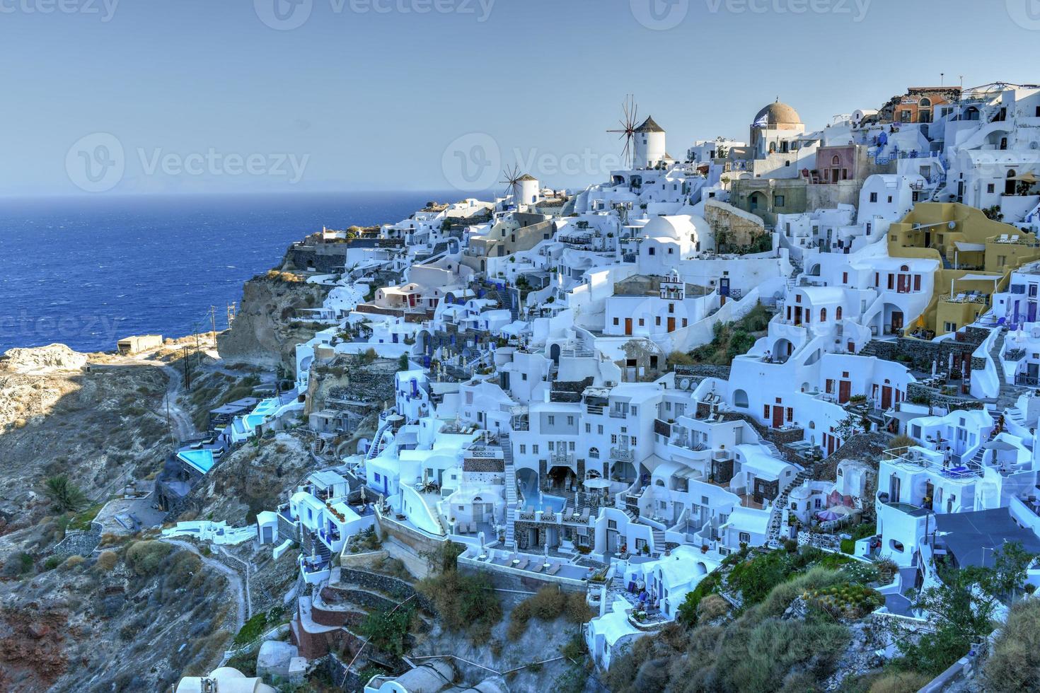 Charming view Oia village on Santorini island, Greece. Traditional famous blue dome church over the Caldera in Aegean sea. Traditional blue and white Cyclades architecture. photo