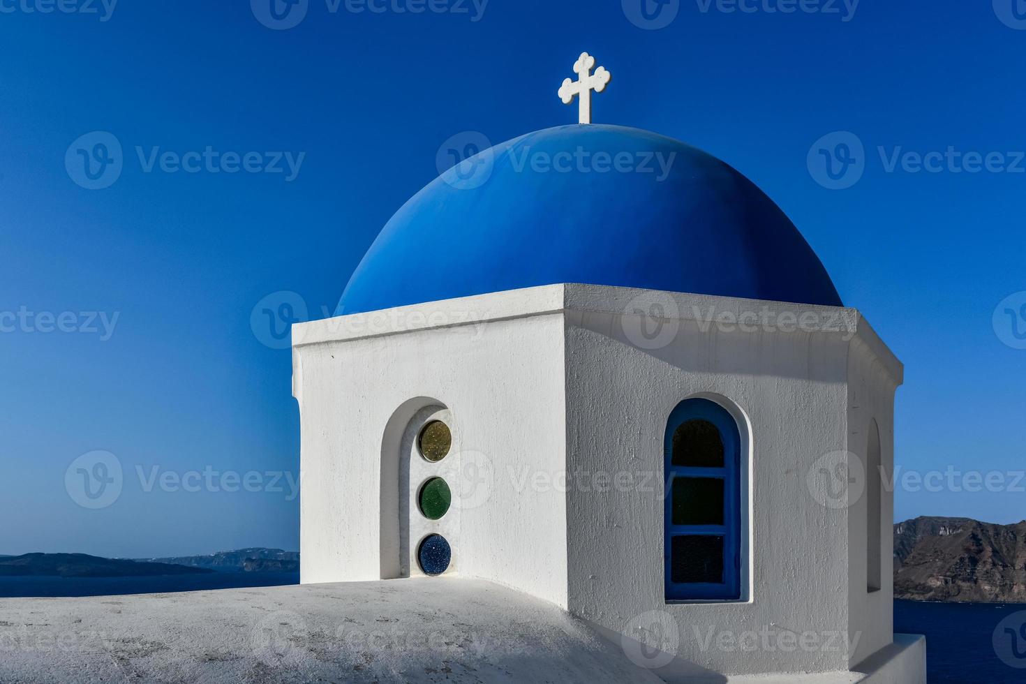 Charming view Oia village on Santorini island, Greece. Traditional famous blue dome church over the Caldera in Aegean sea. Traditional blue and white Cyclades architecture. photo