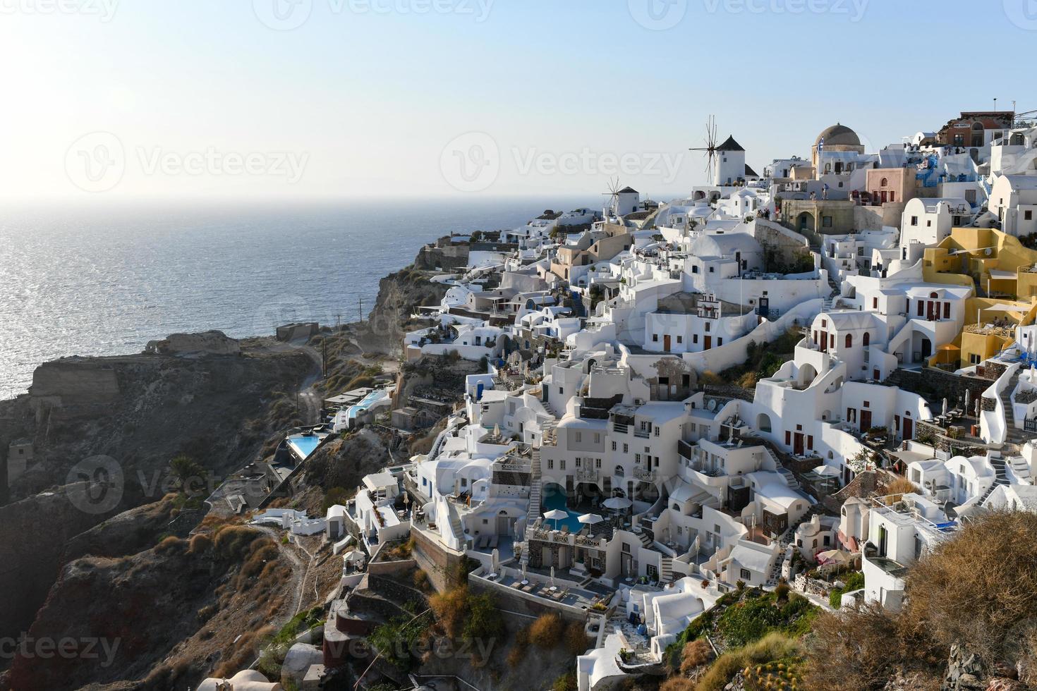 Charming view Oia village on Santorini island, Greece. Traditional famous blue dome church over the Caldera in Aegean sea. Traditional blue and white Cyclades architecture. photo
