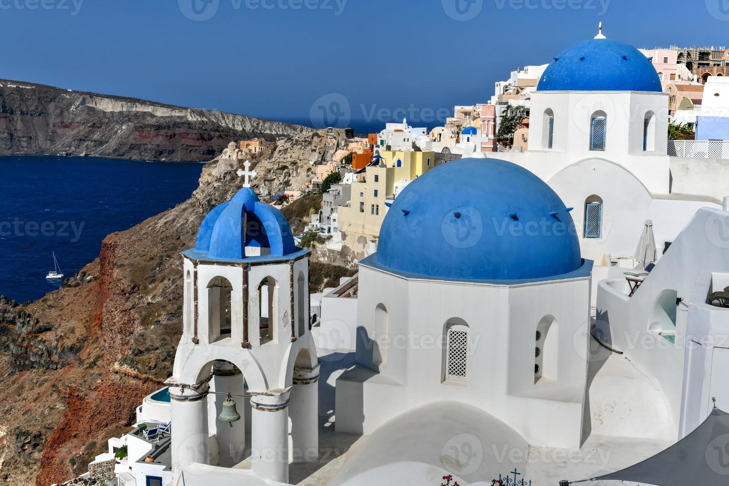 Charming view Oia village on Santorini island, Greece. Traditional famous blue dome church over the Caldera in Aegean sea. Traditional blue and white Cyclades architecture. photo