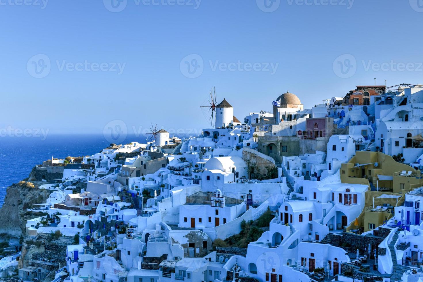 Charming view Oia village on Santorini island, Greece. Traditional famous blue dome church over the Caldera in Aegean sea. Traditional blue and white Cyclades architecture. photo