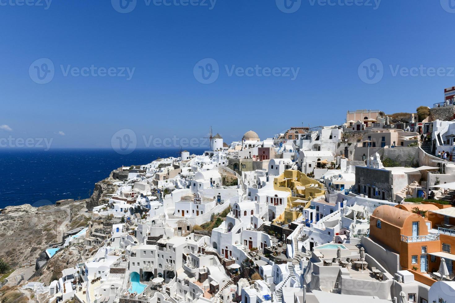 Charming view Oia village on Santorini island, Greece. Traditional famous blue dome church over the Caldera in Aegean sea. Traditional blue and white Cyclades architecture. photo