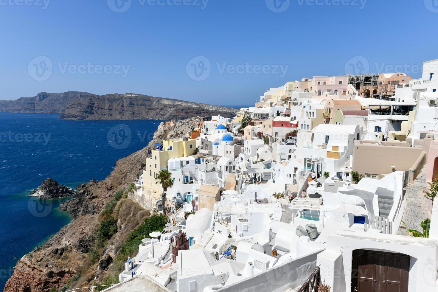 Charming view Oia village on Santorini island, Greece. Traditional famous blue dome church over the Caldera in Aegean sea. Traditional blue and white Cyclades architecture. photo